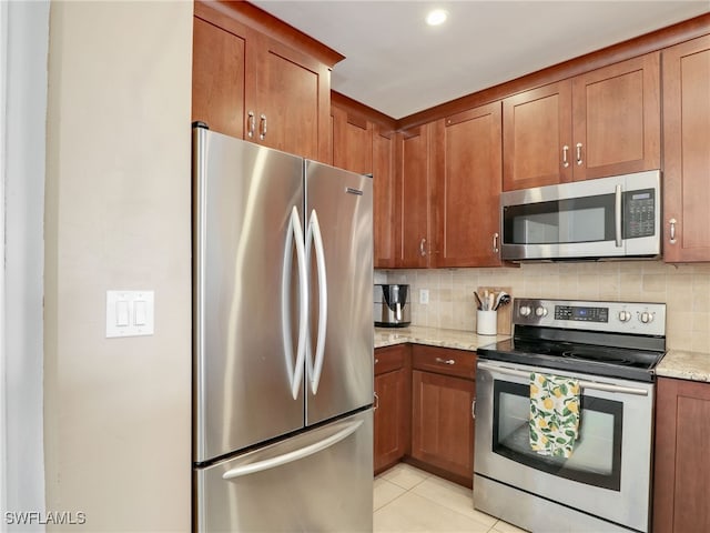 kitchen with light tile patterned flooring, stainless steel appliances, decorative backsplash, and light stone countertops