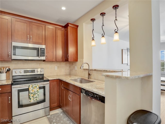 kitchen featuring light stone countertops, stainless steel appliances, sink, hanging light fixtures, and kitchen peninsula