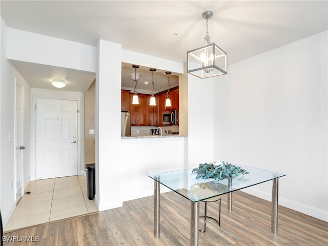 unfurnished dining area featuring light wood-type flooring and an inviting chandelier