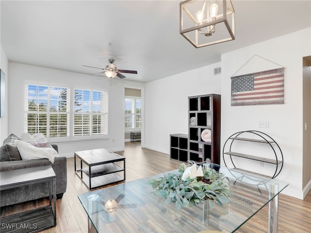 living room featuring ceiling fan with notable chandelier and wood-type flooring