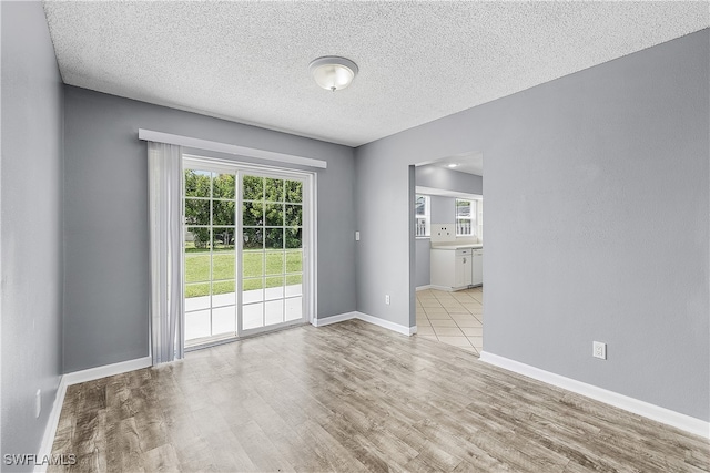 unfurnished room with a textured ceiling and light hardwood / wood-style flooring