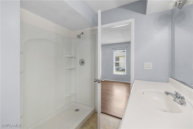 bathroom featuring a textured ceiling, hardwood / wood-style flooring, and walk in shower