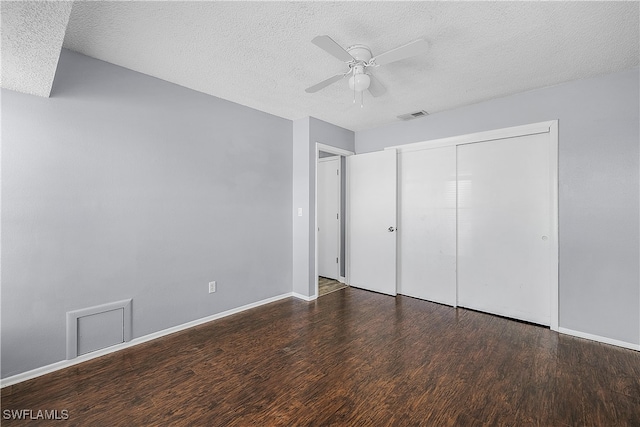 unfurnished bedroom featuring dark wood-type flooring, a textured ceiling, ceiling fan, and a closet