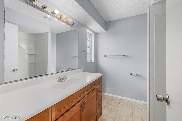 bathroom with vanity, a textured ceiling, walk in shower, and tile patterned floors