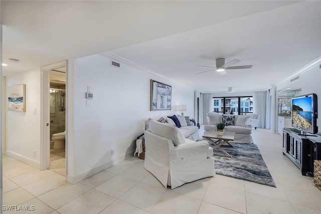 living area with light tile patterned floors, visible vents, baseboards, ceiling fan, and crown molding