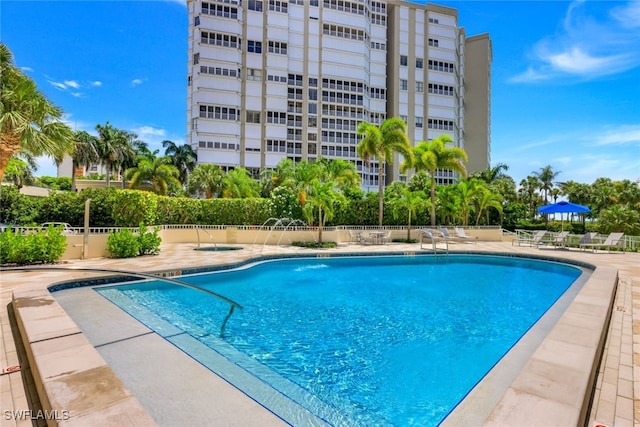 community pool with a patio area, fence, and a community hot tub