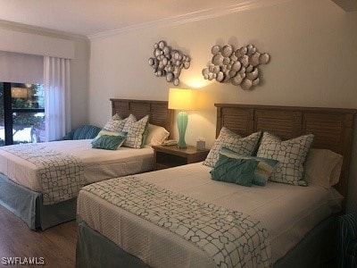 bedroom featuring ornamental molding and wood finished floors