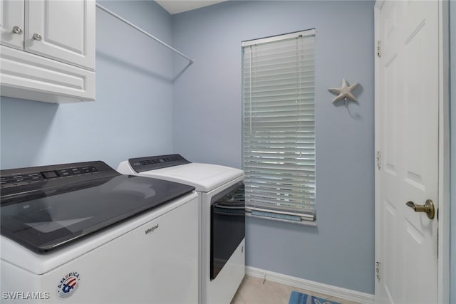 washroom with light tile patterned floors, cabinets, and washer and dryer