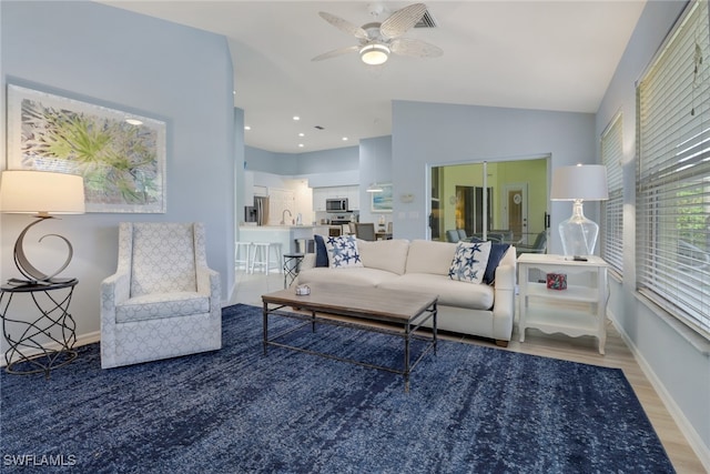 living room featuring lofted ceiling, ceiling fan, wood-type flooring, and sink