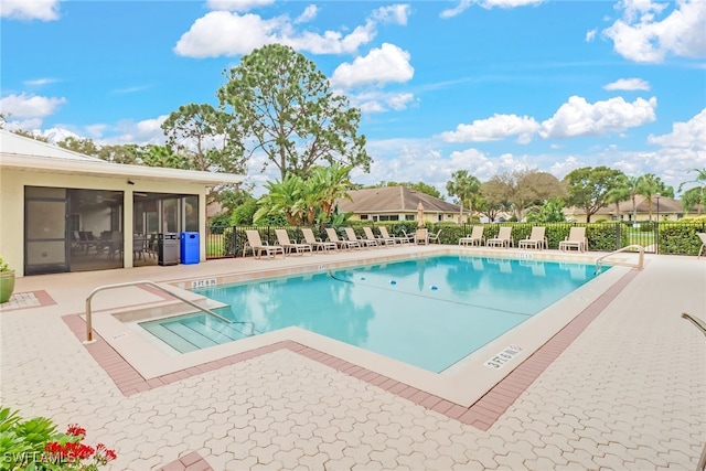 view of swimming pool with a patio area and a sunroom