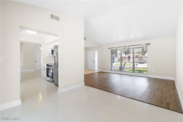 unfurnished living room with light tile patterned flooring and lofted ceiling