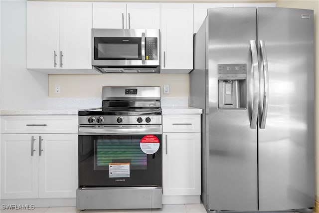 kitchen featuring light tile patterned flooring, stainless steel appliances, and white cabinets