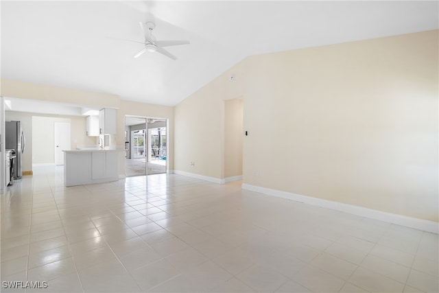 spare room with ceiling fan, light tile patterned floors, and vaulted ceiling