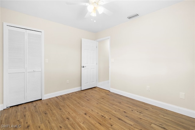 unfurnished bedroom with ceiling fan, a closet, and hardwood / wood-style flooring