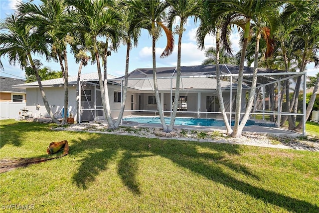 back of house with a lanai and a lawn