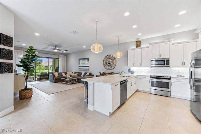 kitchen with ceiling fan, stainless steel appliances, kitchen peninsula, and white cabinetry