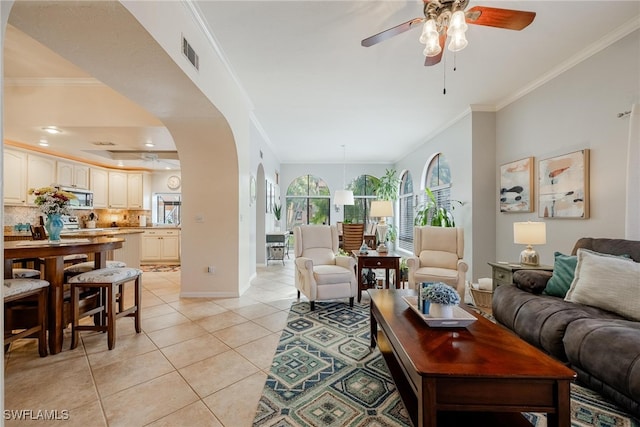 tiled living room with ceiling fan and ornamental molding