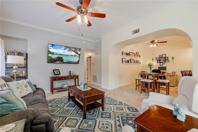 living area with light tile patterned floors, visible vents, arched walkways, a ceiling fan, and crown molding