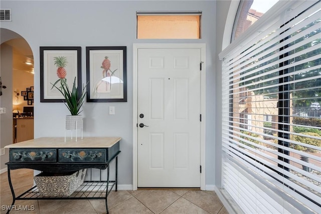 entryway with light tile patterned floors, visible vents, arched walkways, and baseboards