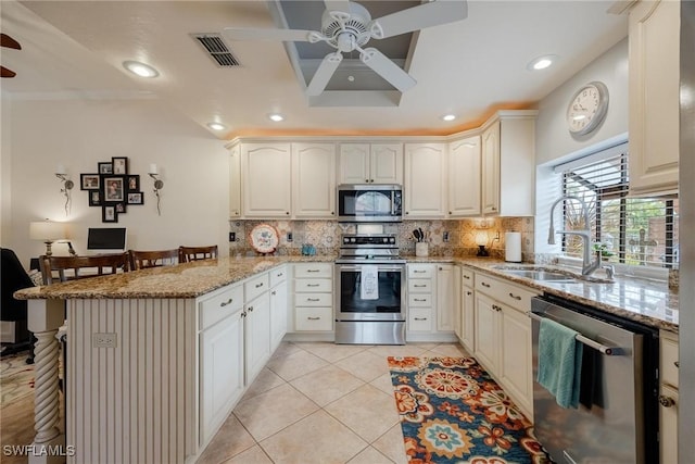 kitchen with light tile patterned floors, a peninsula, a sink, stainless steel appliances, and backsplash