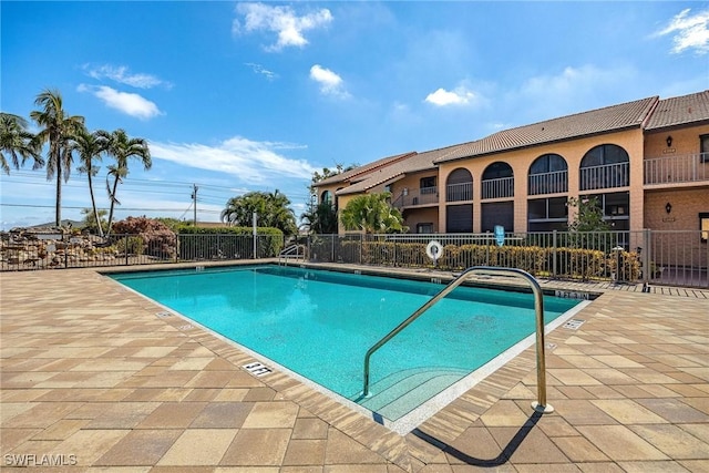 community pool featuring fence and a patio