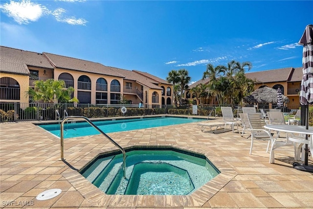 pool featuring a hot tub, fence, and a patio