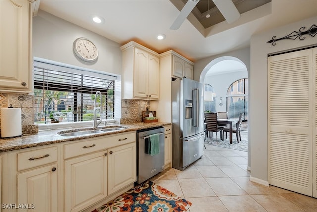 kitchen with tasteful backsplash, stainless steel appliances, light stone counters, sink, and ceiling fan