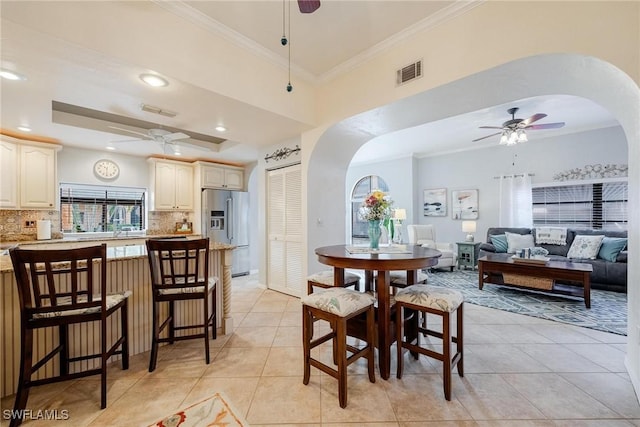 dining area featuring arched walkways, ceiling fan, light tile patterned floors, visible vents, and ornamental molding