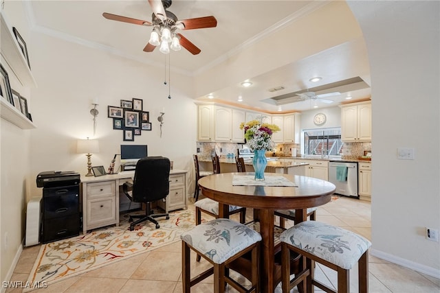 tiled dining room featuring built in desk, ceiling fan, a tray ceiling, and ornamental molding