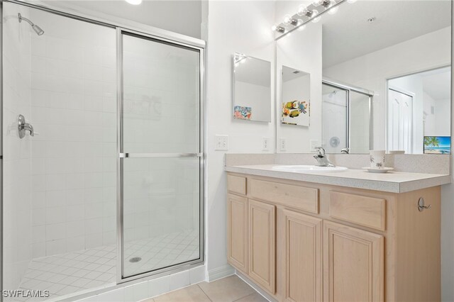 bathroom with a shower with door, vanity, and tile patterned floors