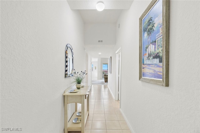 hallway with a textured ceiling and light tile patterned floors