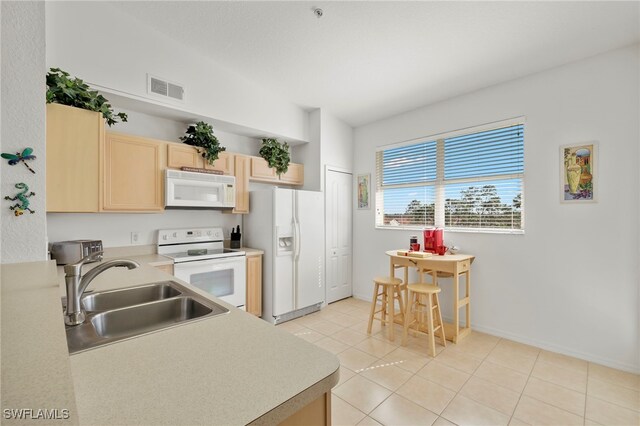 kitchen featuring white appliances, light brown cabinetry, sink, and light tile patterned flooring