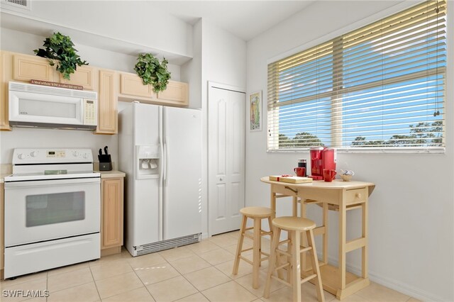 kitchen with white appliances, light tile patterned floors, and light brown cabinetry