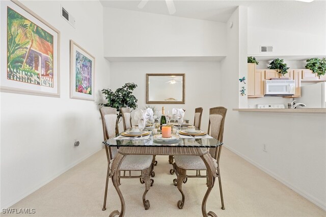 dining space featuring light colored carpet, sink, and high vaulted ceiling