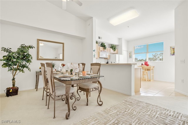 dining room with high vaulted ceiling, ceiling fan, and light colored carpet