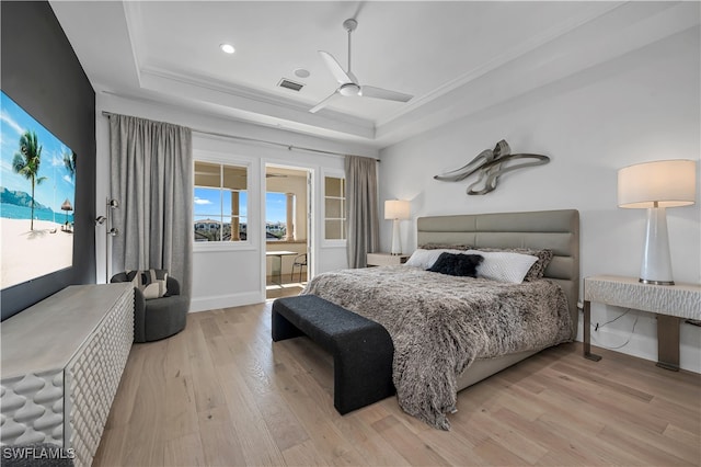 bedroom featuring ceiling fan, a raised ceiling, light hardwood / wood-style floors, and ornamental molding