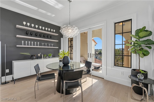 dining space with crown molding, french doors, an inviting chandelier, and light hardwood / wood-style floors