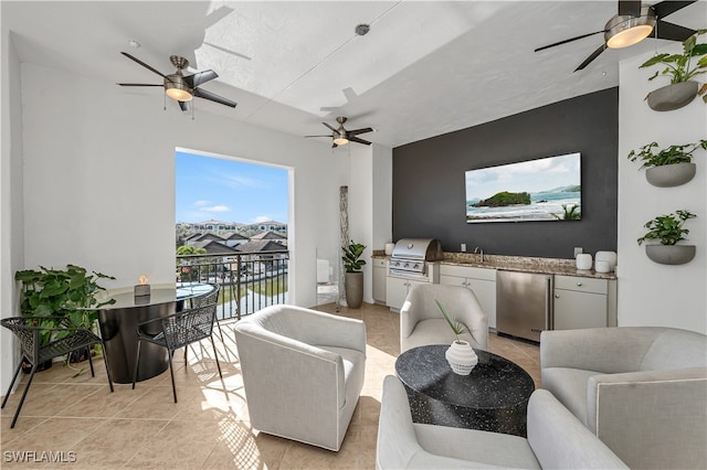 living room with ceiling fan, light tile patterned floors, a textured ceiling, and sink