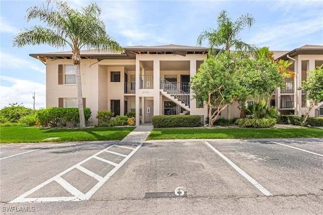 view of property featuring stairs and uncovered parking