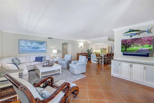 living area featuring light tile patterned floors, visible vents, arched walkways, and crown molding