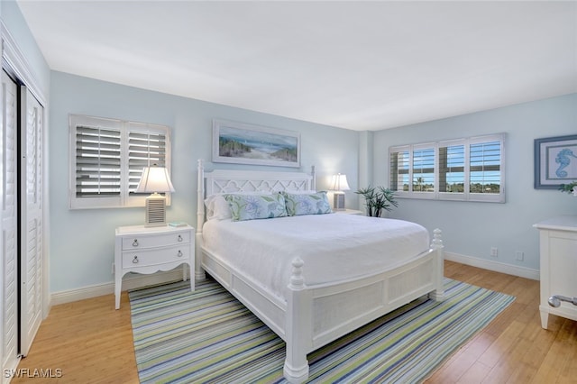 bedroom featuring a closet, light wood-type flooring, and baseboards