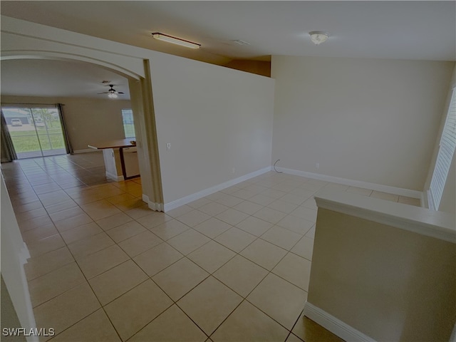 tiled empty room with ceiling fan and vaulted ceiling