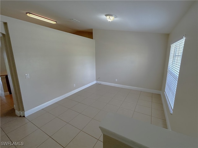 unfurnished room with lofted ceiling and light tile patterned floors