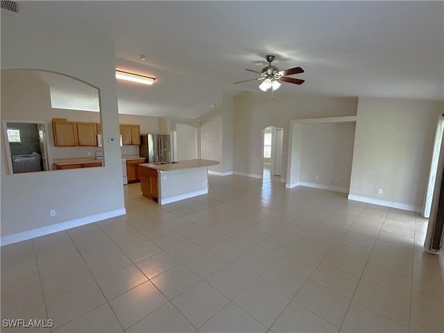 unfurnished living room featuring sink, ceiling fan, vaulted ceiling, and light tile patterned floors