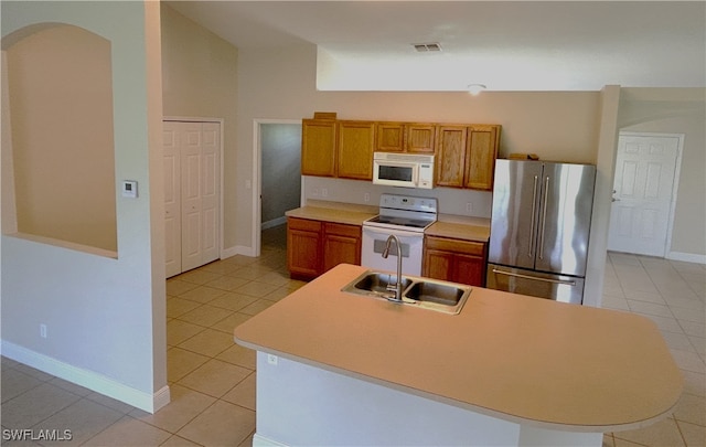 kitchen with white appliances, light tile patterned flooring, sink, vaulted ceiling, and a kitchen island with sink