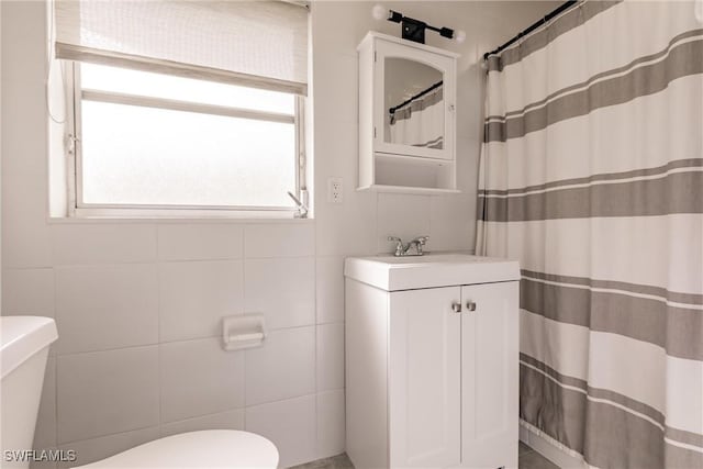 bathroom with a shower with curtain, vanity, toilet, and tile walls