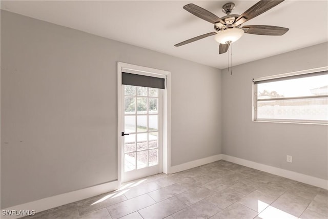 spare room featuring ceiling fan, light tile patterned floors, plenty of natural light, and baseboards