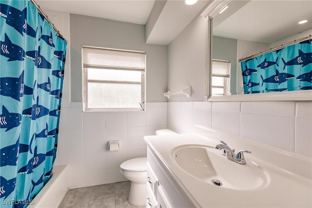 full bathroom with toilet, a wainscoted wall, tile walls, vanity, and tile patterned floors