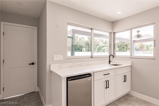 kitchen featuring stainless steel fridge, baseboards, light countertops, white cabinetry, and a sink