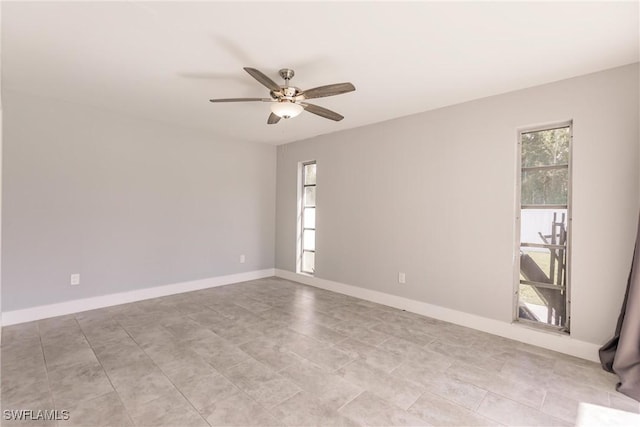 empty room featuring a ceiling fan and baseboards